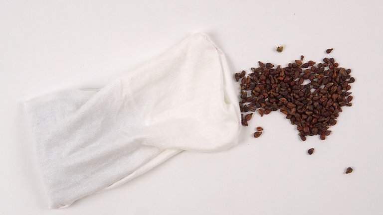 Das Stoffstück für das Füllsäckchen rechts auf rechts zusammenklappen und die offenen Seiten bis auf eine 5 cm große Wendeöffnung in der Mitte der kurzen Seite zusammennähen. Das Säckchen auf rechts wenden und die Traubenkerne oder das Füllgranulat einfüllen.