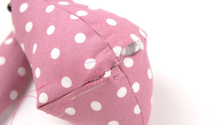 Das Füllsäckchen so in den Körper schieben, dass es im hinteren Bereich des Bodens sitzt. Noch vorhandene Hohlräume mit Füllwatte ausstopfen. Die Wendeöffnung von Hand mit Matratzenstichen schließen.