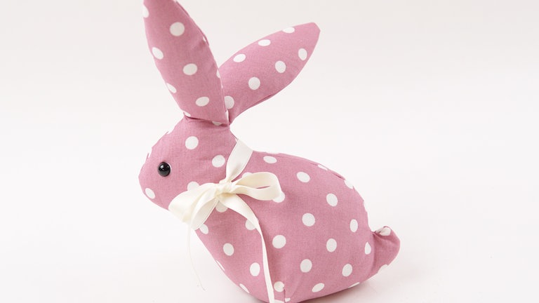 Das Satinband mit einer Schleife um den Hals binden und die Bandenden schräg abschneiden.