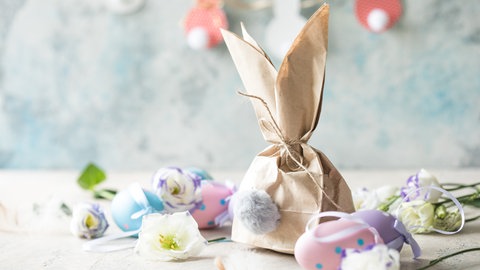 Osterdekoration mit Eiern, Blumen und Papierosterhase