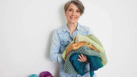 Tanja Steinbach mit verschiedenen gestrickten Sachen auf dem Arm