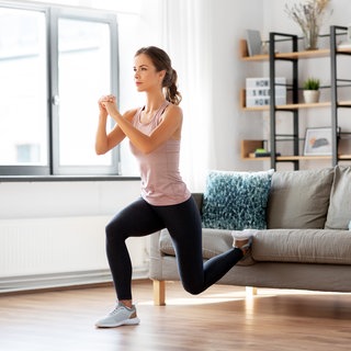 Frau macht Sportübungen im Wohnzimmer
