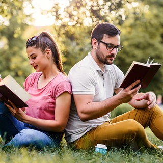 Frau und Mann lesen im Park