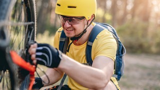 Mann repariert Fahrrad - Notfallpaket für die Radtour