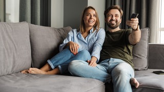 Paar sitzt auf der Couch und guckt TV