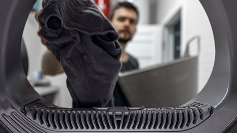 Sport- und Funktionskleidung richtig waschen - Mann vor Waschmaschine