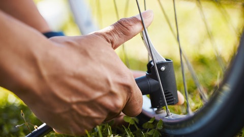 Mann pumpt Schlauch auf - Notfallpaket für die Radtour