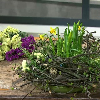 Ein Osternest mit Eiern und Narzissen