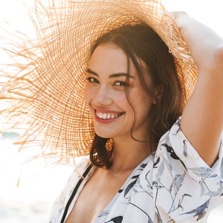 Frau am Strand im Bikini mit Strohhut