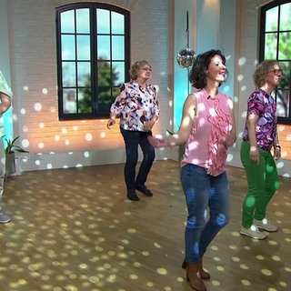 drei Frauen und ein Mann tanzen Line-Dance
