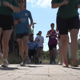 Jogger*innen und ein Mann im Rollstuhl laufen Marathon