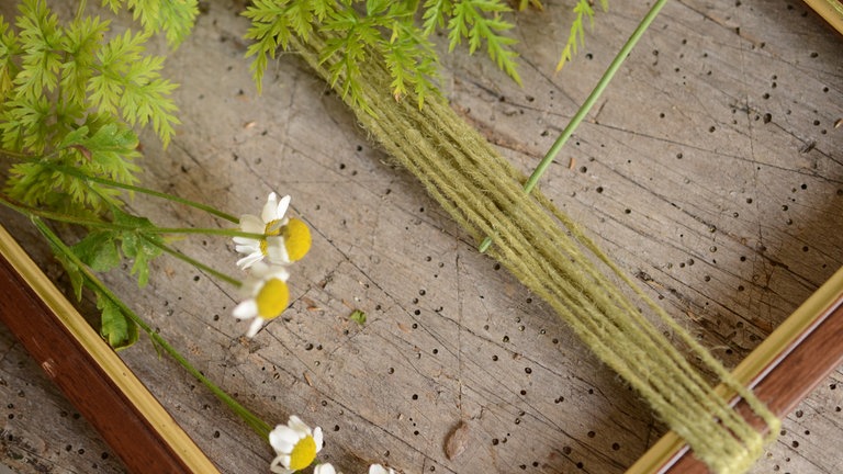Die Blumenstängel durch die Schnur weben. 