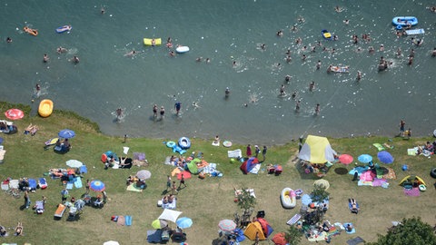 Menschen sonnen sich in Freiburg am Tunisee.