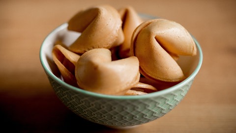 Silvester Glückskekse anstelle von Bleigießen - Eine hellgrüne Porzellanschale mit vielen Glückskeksen steht auf eine hellen Holzuntergrund