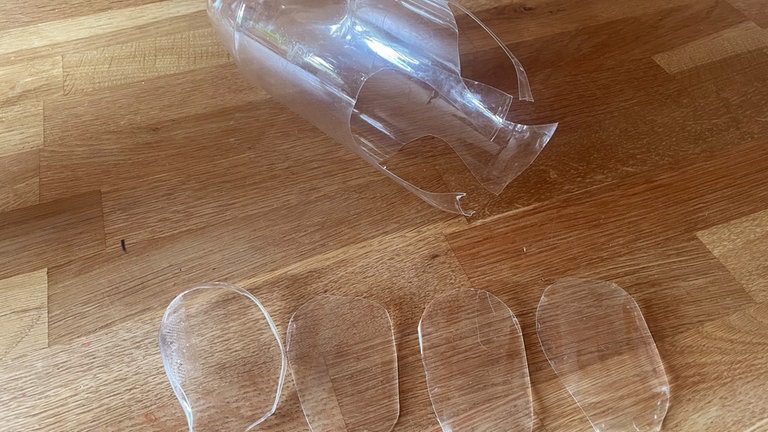 Entlang des Randes der unteren Flaschenhälfte mit der Schere vier Blütenblätter ausschneiden.