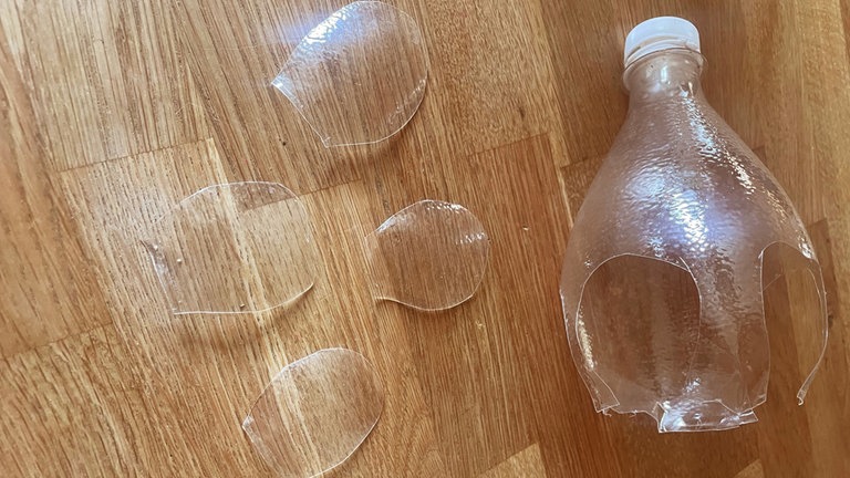 Dann entlang des Randes der oberen Flaschenhälfte vier etwas kleinere Blütenblätter ausschneiden. 