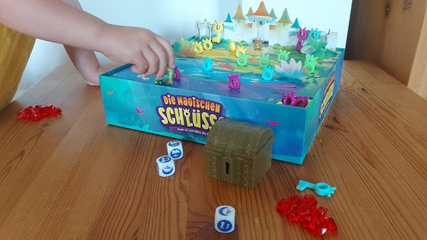 Eine Kinderhand greift nach der Spielfigur bei dem aufgebauten Brettspiel "Die magischen Schlüssel": Die Jury "Spiel des Jahres" hat den Titel zum "Kinderspiel des Jahres 2024" nominiert.