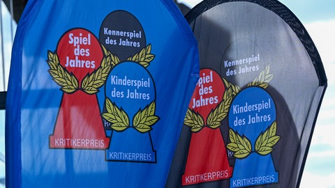 Fahnen mit drei Spielfiguren: Diese "Pöppel" in den Farben Rot (Familie), Anthrazit (Kenner) und Blau (Kinder) sind die drei Preise, die die Jury "Spiel des Jahres" jedes Jahr verleiht. 