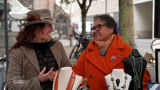 Zwei Frauen lächeln sich auf dem Flohmarkt an