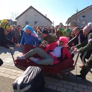 Männer schieben ein Sofa bei einem Rennen durch die Straßen
