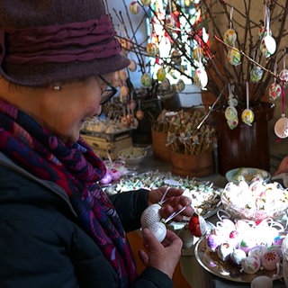 Dapfener Eiermarkt 2025: Eine Frau schaut sich die verzierten Eier an