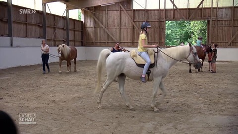 Kinder reiten in einer Reiterhalle