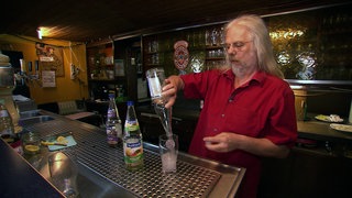 Wirt Walter Dieterle steht hiner der Theke der Kneipe Hirsch in Glems und schenkt Getränke aus.