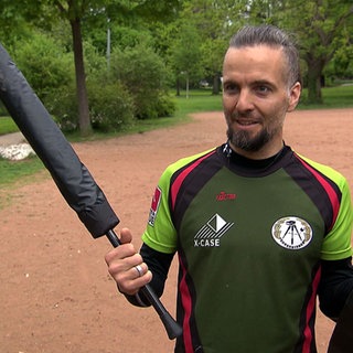 Frederik Langeneckert aus Freiburg spielt Jugger. Er hält eine Pompfe in der Hand.