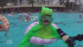 Eine verkleidete Frau wird im Schwimmbecken in einem Schwimmring interviewt