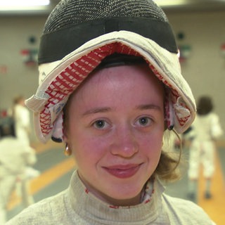 Die 15-jährige Ruxandra ist Fechterin beim Fechtverein TV Cannstatt. Sie trägt Fechtkleidung und hat ihre Fechtmaske hochgeschoben.