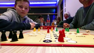 Ein Junge sitzt bei einem Turnier an einem Mensch-ärgere-dich-nicht-Spielbrett