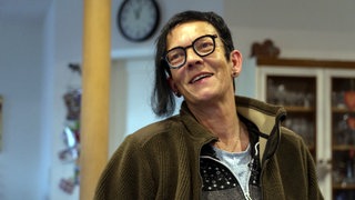 Claudia Walz trägt eine schwarze Brille, kurze Haare mit einer langen Strähne und Ohrringe.