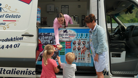 Frau verkauft Speiseeis aus Eismobil