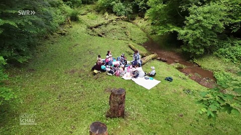 Sonja Faber-Schrecklein sitzt zusammen mit einer Kindergruppe im Wald