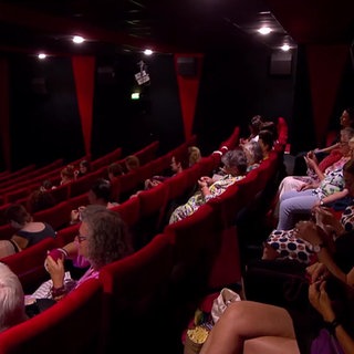 Eine Gruppe Frauen sitzt in einem Kinosaal und strickt