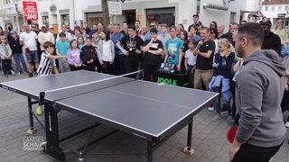 Viele Menschen sehen zwei Personen beim Tischtennis spielen zu