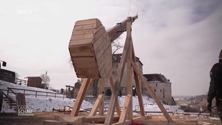 Ein selbstgebauter Katapult aus Holz schießt einen Strohballen in die Luft