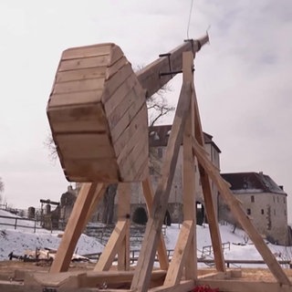 Ein selbstgebauter Katapult aus Holz schießt einen Strohballen in die Luft