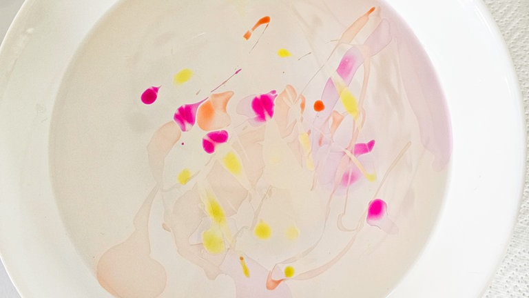 Dazu jede Farbe rasch hintereinander ins Wasser geben (mit geringem Abstand zur Wasseroberfläche) und die Flasche direkt so hin und her bewegen, dass sich der Nagellack gut verteilt und sich schöne Muster bilden.