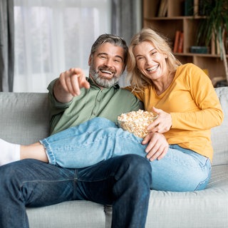 Älteres Paar sitzt auf der Couch mit Popcorn