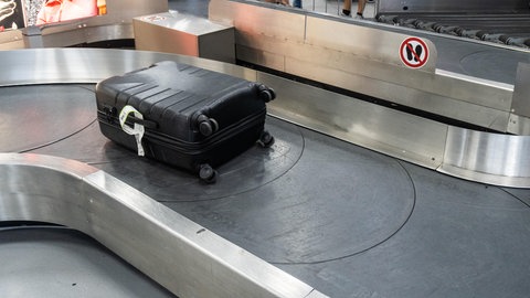 Ein Koffer liegt auf einem Gepäckband am Flughafen | Drama im Urlaub: Das könnt ihr tun, wenn der Koffer verloren ist