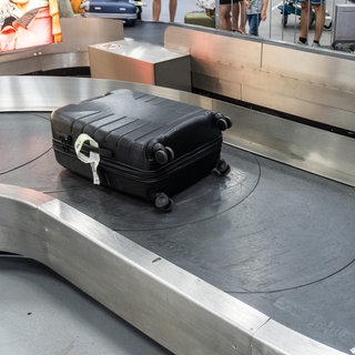 Ein Koffer liegt auf einem Gepäckband am Flughafen | Drama im Urlaub: Das könnt ihr tun, wenn der Koffer verloren ist
