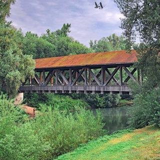 Eine Holzbrücke führt über den Kraichbach. Der Radweg führt überwiegend bergab. Deshalb ist der Kraichradweg ein sehr guter Tipp für einen Ausflug mit der ganzen Familie.
