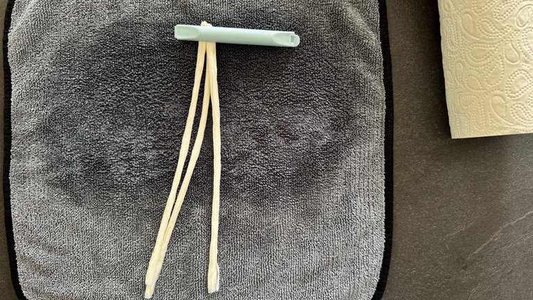 Mit einer Wäscheklammer oder einem Clip, drei gerollte Schnüre festhalten und zu einem Zöpfchen flechten.