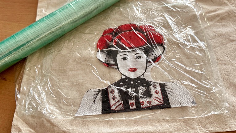 Das Motiv in Frischhaltefolie einwickeln. Die Folie sollte vor und hinter der Serviette sein. 