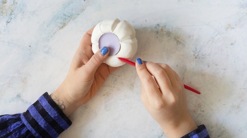 Die eingedrückten Linien können nun mit einem Modellierwerkzeug oder einem stumpfen Messer nachgezogen werden, damit der Kürbis plastischer wirkt und eine natürlichere Form erhält.