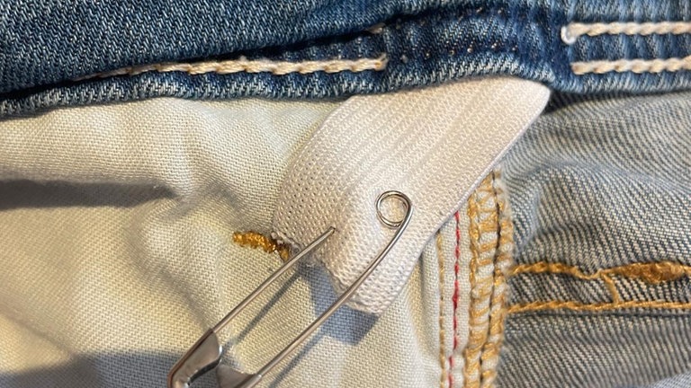 Das Gummiband mit Hilfe einer Sicherheitsnadel in den rückwärtigen Bund einfädeln. 