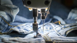 Jeans wird mit der Nämaschine umgenäht