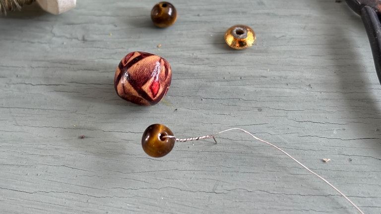 Am Anfang des Drahts 1-2 Perlen befestigen. Das ist nicht nur ein schöner Anfang, sonder gibt dem Draht auch etwas Gewicht und er hängt besser.  