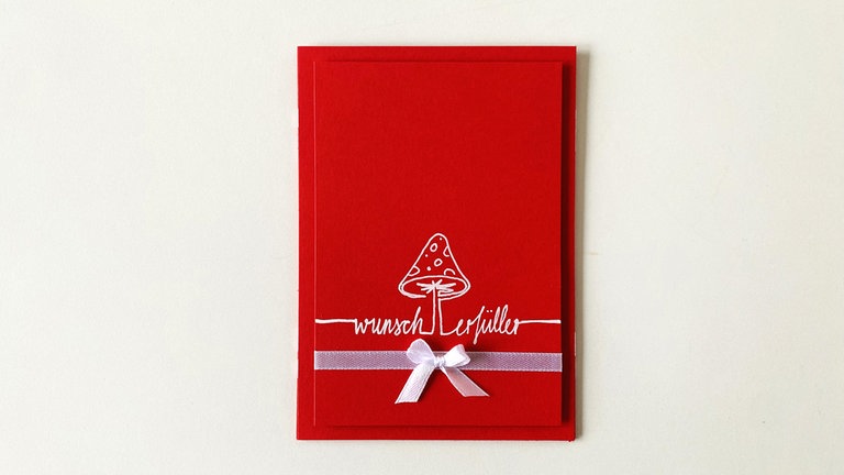 Den Aufleger als nächstes auf die Grundkarte kleben und die Schleife befestigen. Fertig!